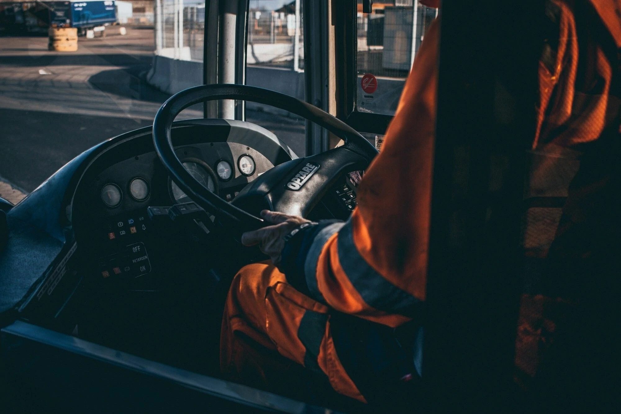 A driver in a hi-vis jacket at the wheel of a bus